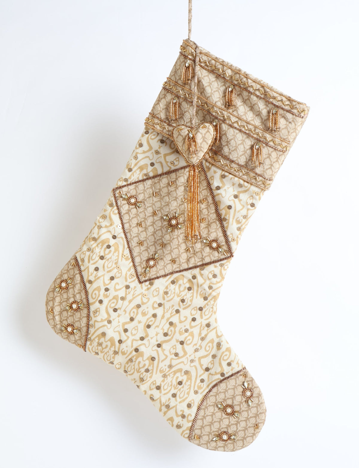 Beige patchwork Christmas stocking with Indian ethnic patterns, gold bead tassels, sequins, and heart-shaped ornament hanging flat