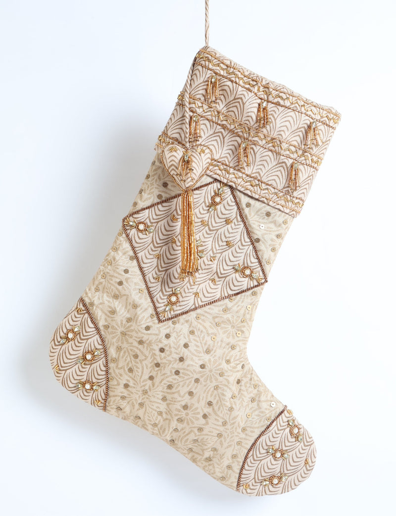 Beige patchwork Christmas stocking with leaf patterns, gold bead tassels, sequins, and embroidered floral details, hanging flat