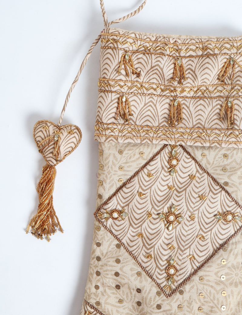 Beige patchwork Christmas stocking with leaf pattern, gold bead embellishments, sequins, and a heart-shaped tassel hanging detail