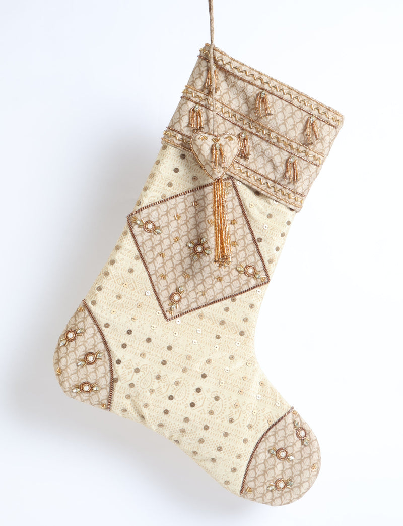 Beige patchwork Christmas stocking with paisley pattern, gold sequins, beads, and tassel embellishments, hanging flat