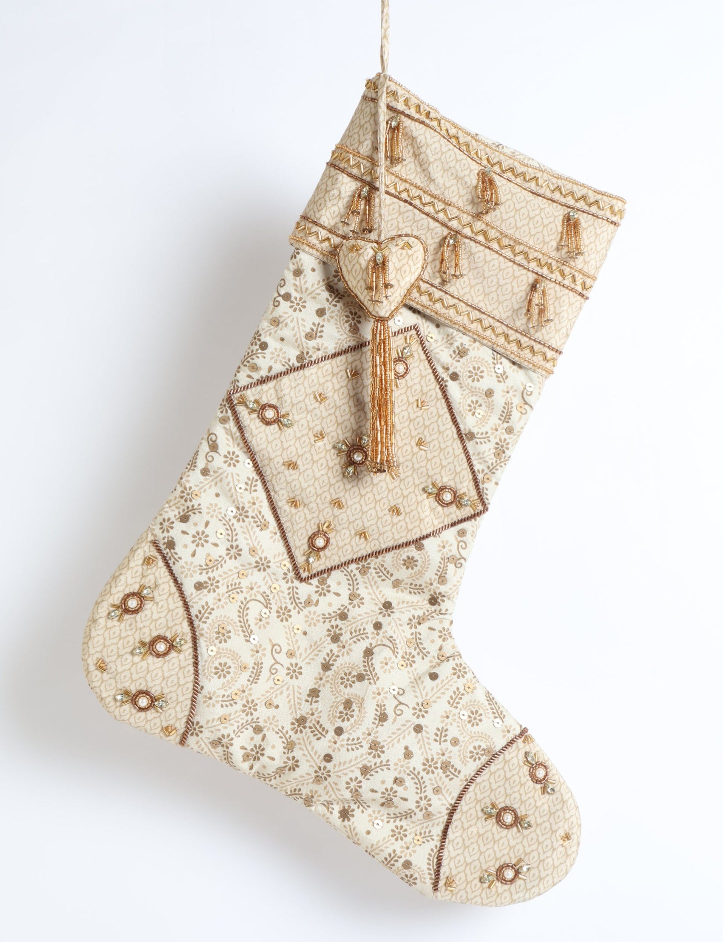 Ivory and cream upcycled sari Christmas stocking with gold hand embroidery, patchwork detailing, and a beaded heart charm tassel — crafted from recycled materials and inspired by circular, fair trade, and eco clothing fashion.