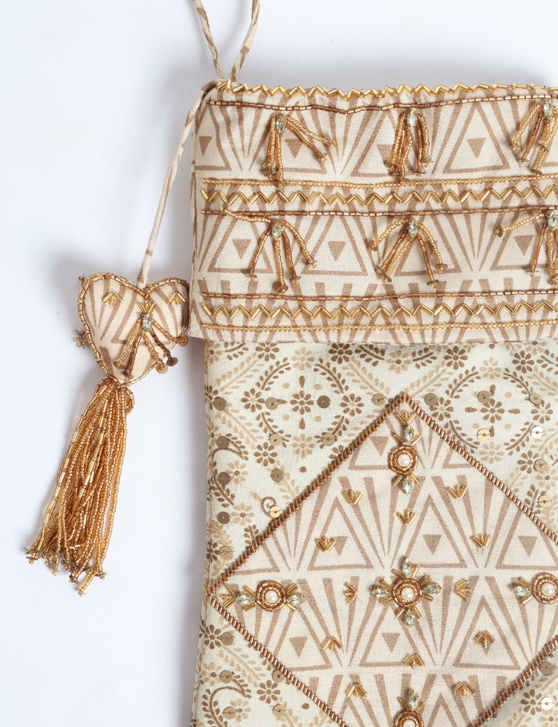 Beige patchwork Christmas stocking with leaf patterns, gold bead embellishments, and a heart-shaped tassel hanging detail