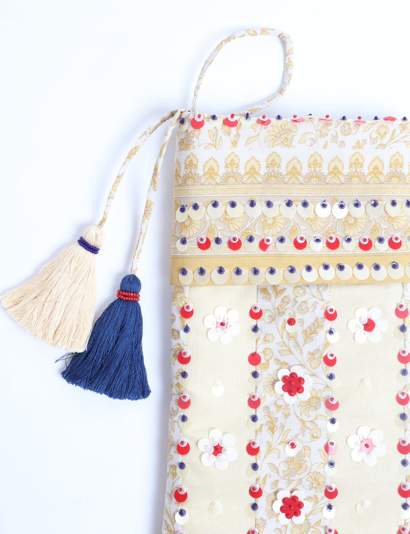 Flower Christmas stocking in cream and gold fabric with red, white, and purple sequins and two tassels hanging from the top loop