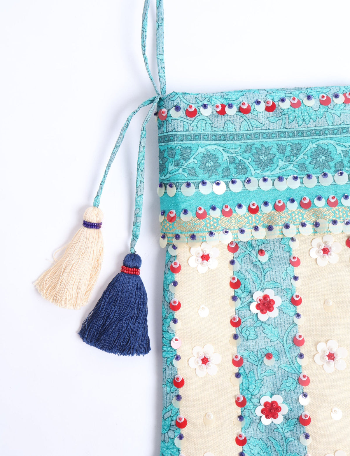Blue and cream flower-patterned Christmas stocking with red, white, and blue sequins and two hanging tassels, front view