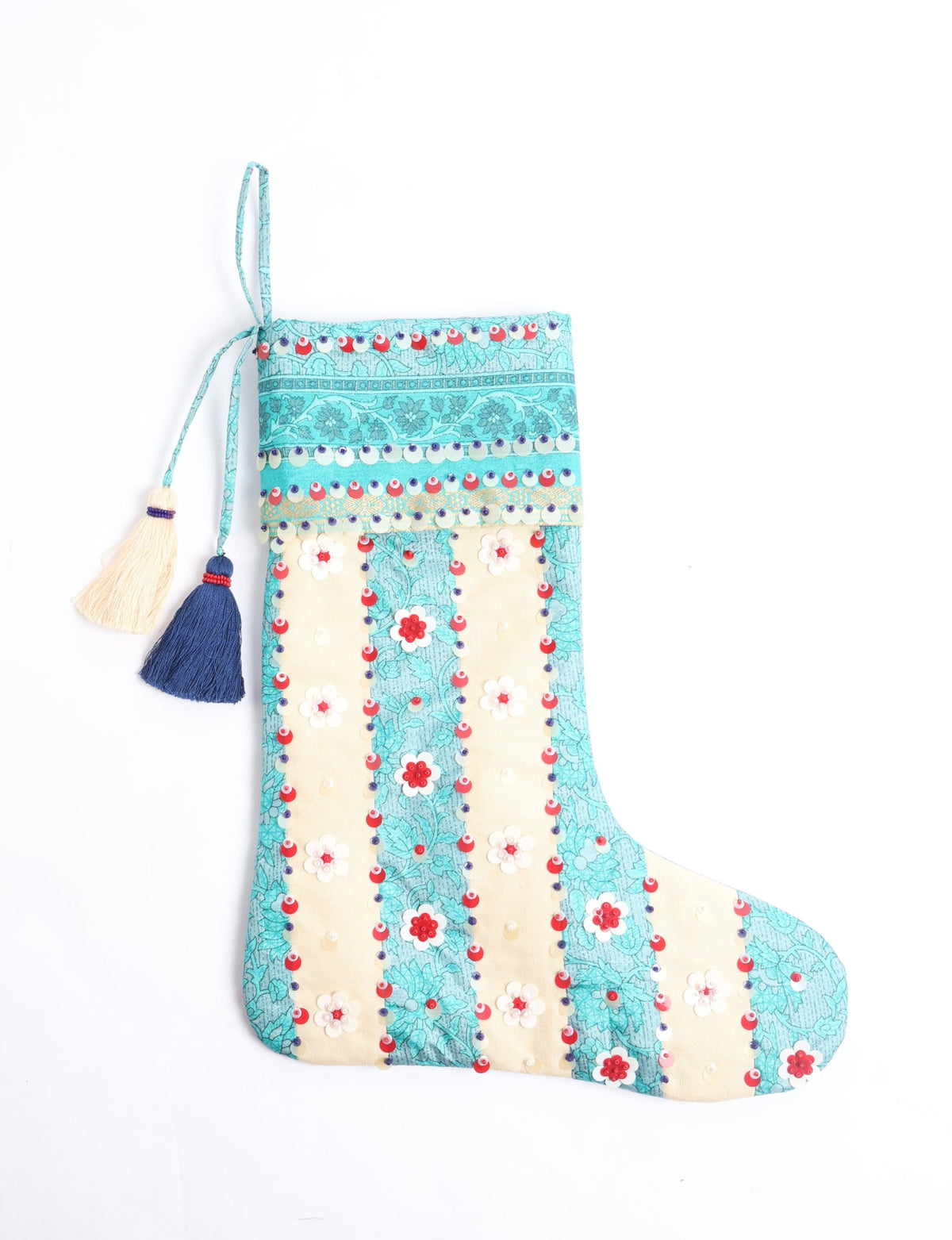 Christmas stocking with turquoise floral pattern, red and white sequins, and blue and cream tassels, flat lay view