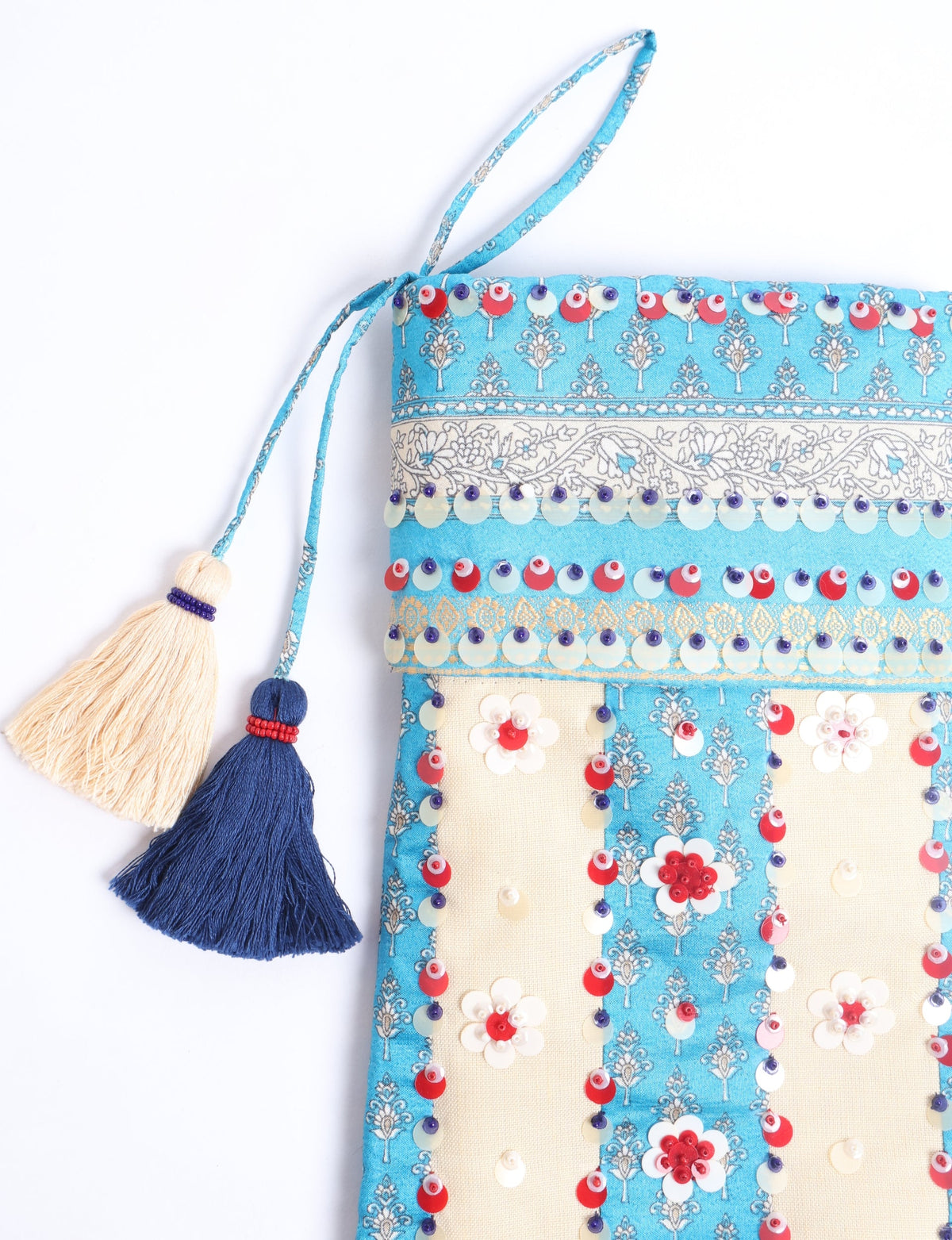 Blue and cream flower-patterned Christmas stocking with red, white, and purple sequins and two tassels hanging from the top loop