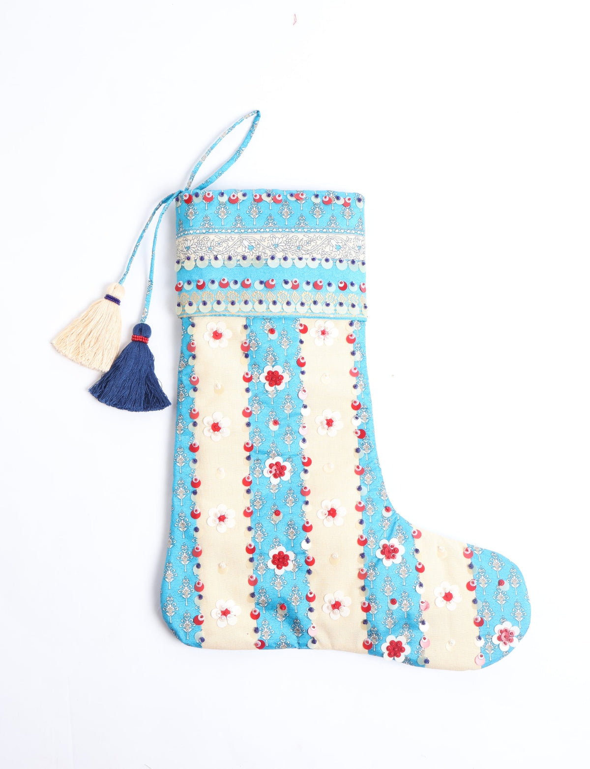 Blue and cream flower-patterned Christmas stocking with red and white sequins and two tassels hanging from the top loop
