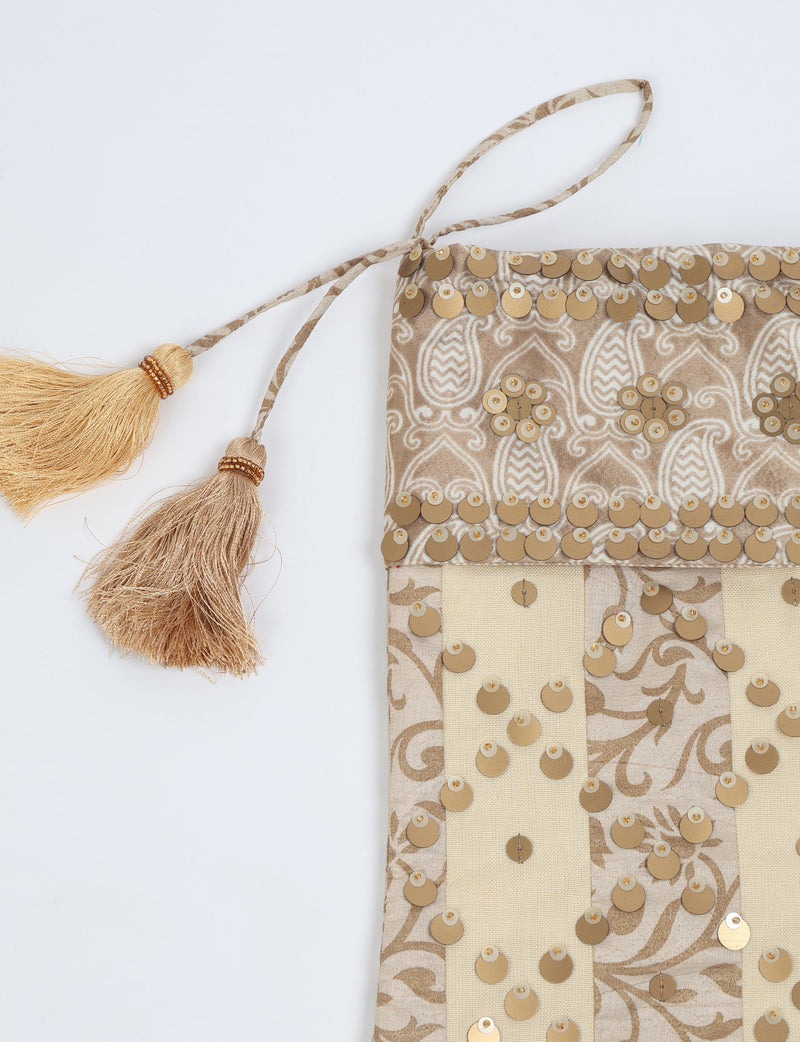 Beige and cream striped Christmas stocking with gold sequins and two gold tassels on hanging loop, flat lay view