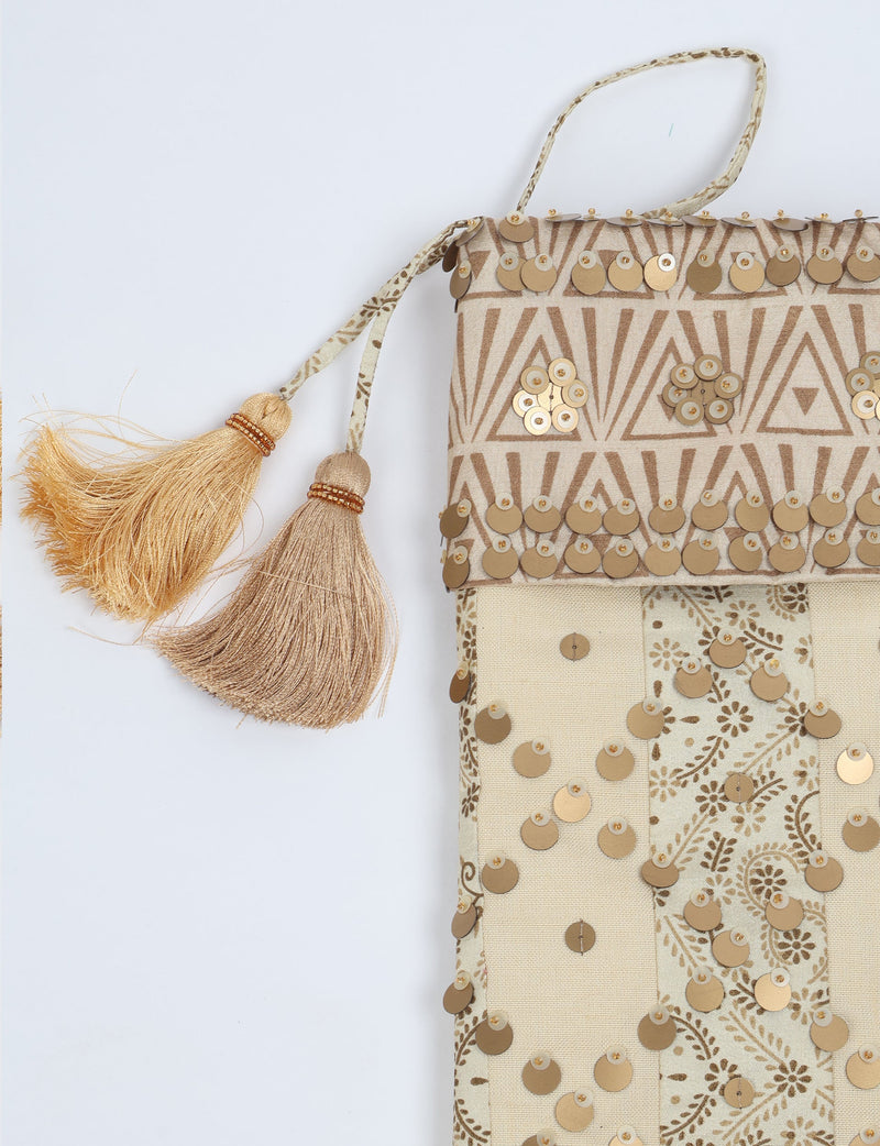 Beige and brown striped Christmas stocking with gold sequins and two beige tassels, flat lay view