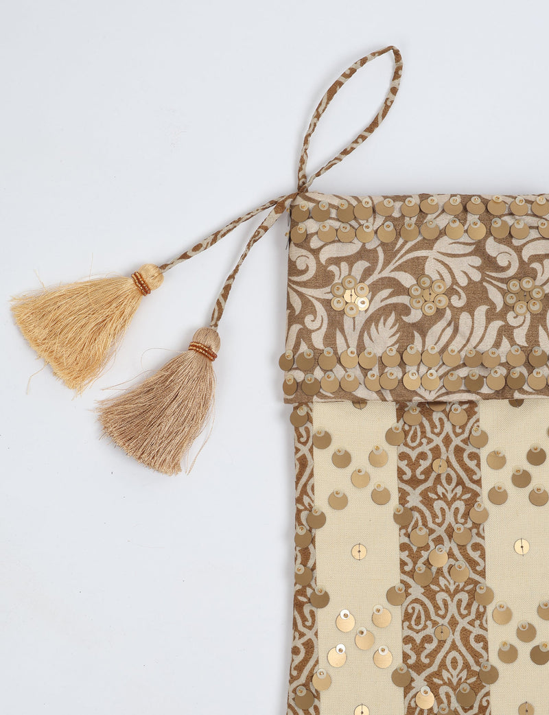 Christmas stocking with beige and brown floral and stripe pattern, gold sequins, and two beige tassels on hanging loop