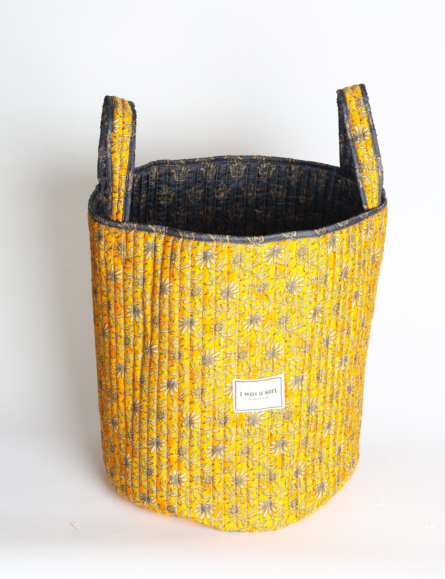 Quilted storage basket with handle in a soft cylindrical design, available in small and medium sizes for home organization.