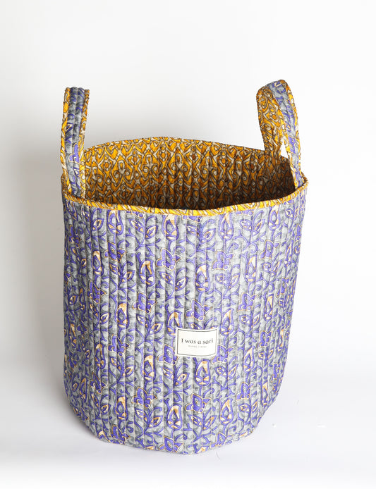 Quilted storage basket with handle in a soft cylindrical design, available in small and medium sizes for home organization.