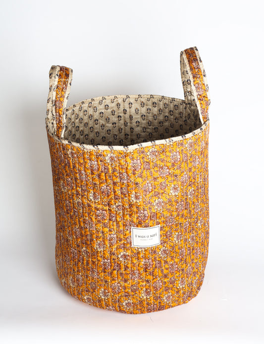 Quilted storage basket with handle in a soft cylindrical design, available in small and medium sizes for home organization.