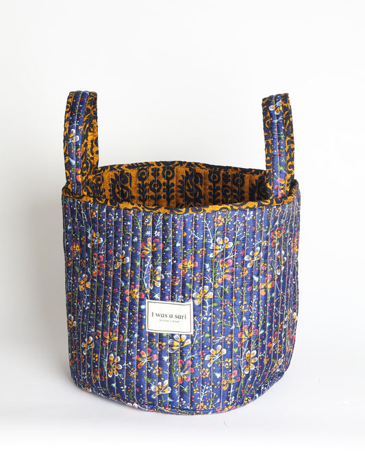 Quilted storage basket with handle in a soft cylindrical design, available in small and medium sizes for home organization.