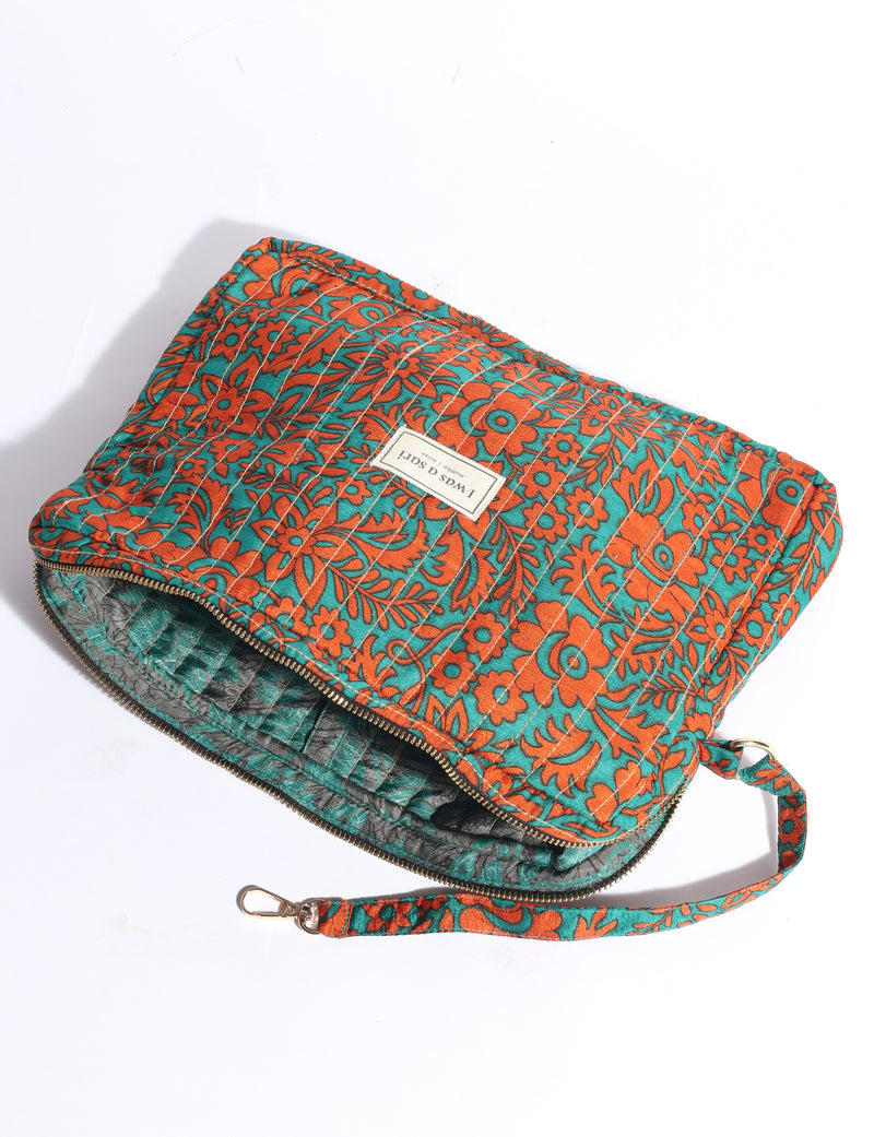 Quilted fabric organizer with orange floral pattern on teal background, zipper closure, and detachable wrist strap, flat lay