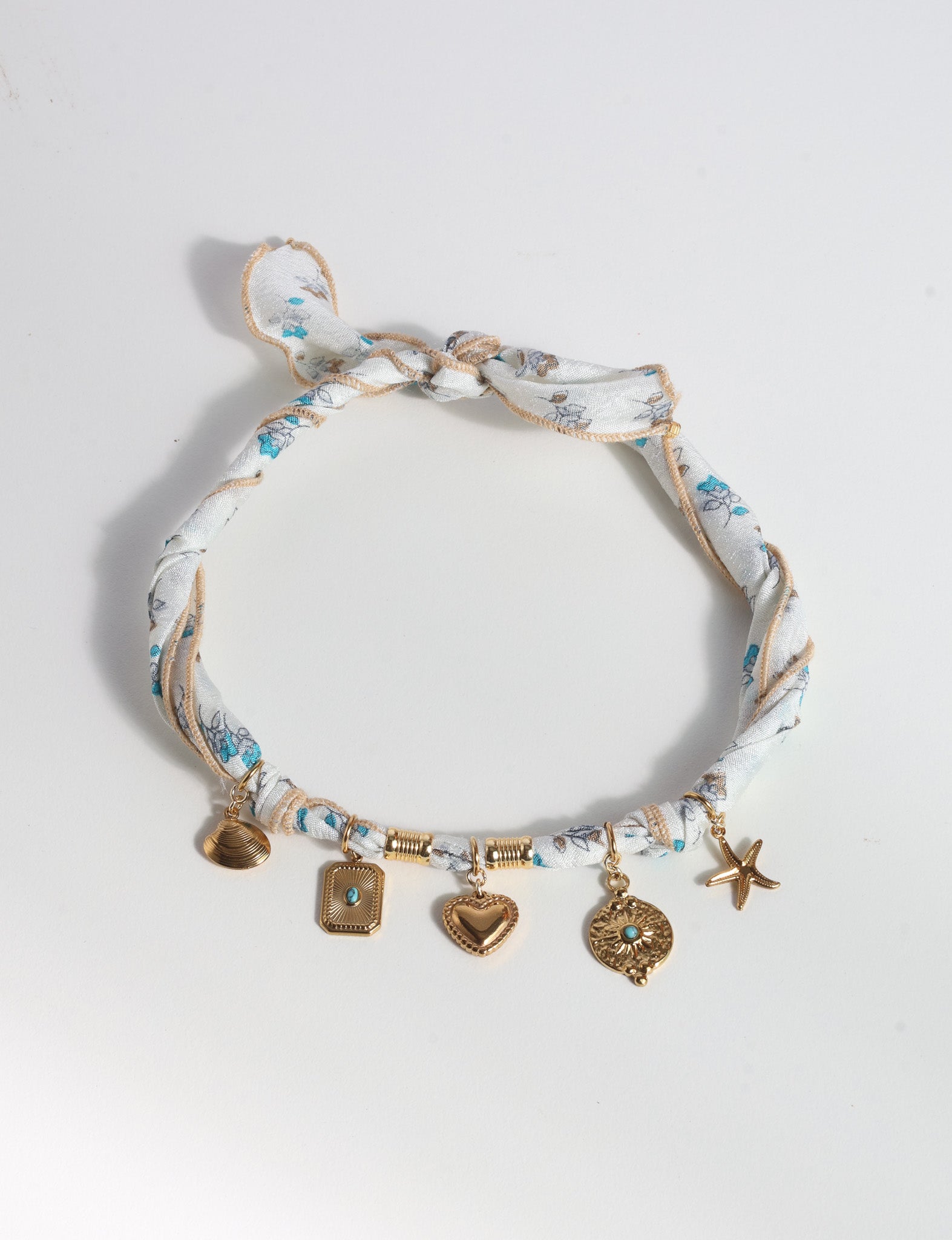 White tropical patterned bandana necklace with gold-tone shell, heart, starfish, and turquoise-accented charms, knotted closure