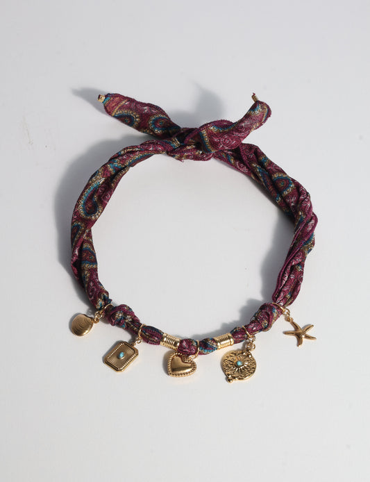 Bandana necklace with gold-plated charms, adjustable tie-back design, stainless steel hardware, handmade statement necklace, sustainable fashion accessory.