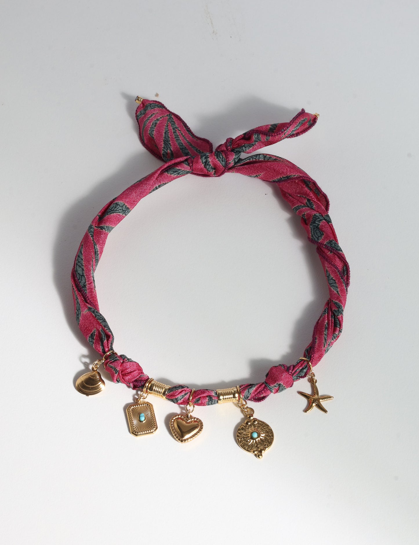 Bandana necklace with gold-plated charms, adjustable tie-back design, stainless steel hardware, handmade statement necklace, sustainable fashion accessory.