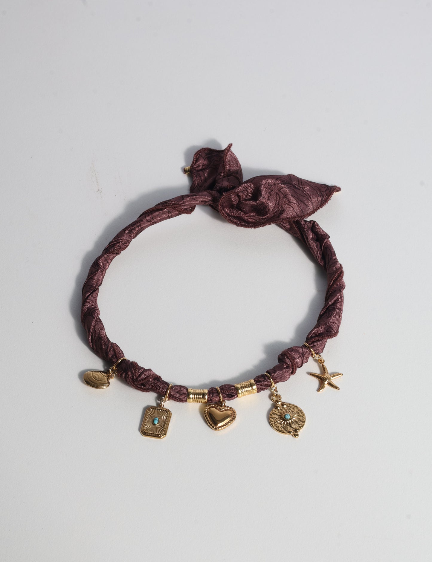 Bandana necklace with gold-plated charms, adjustable tie-back design, stainless steel hardware, handmade statement necklace, sustainable fashion accessory.