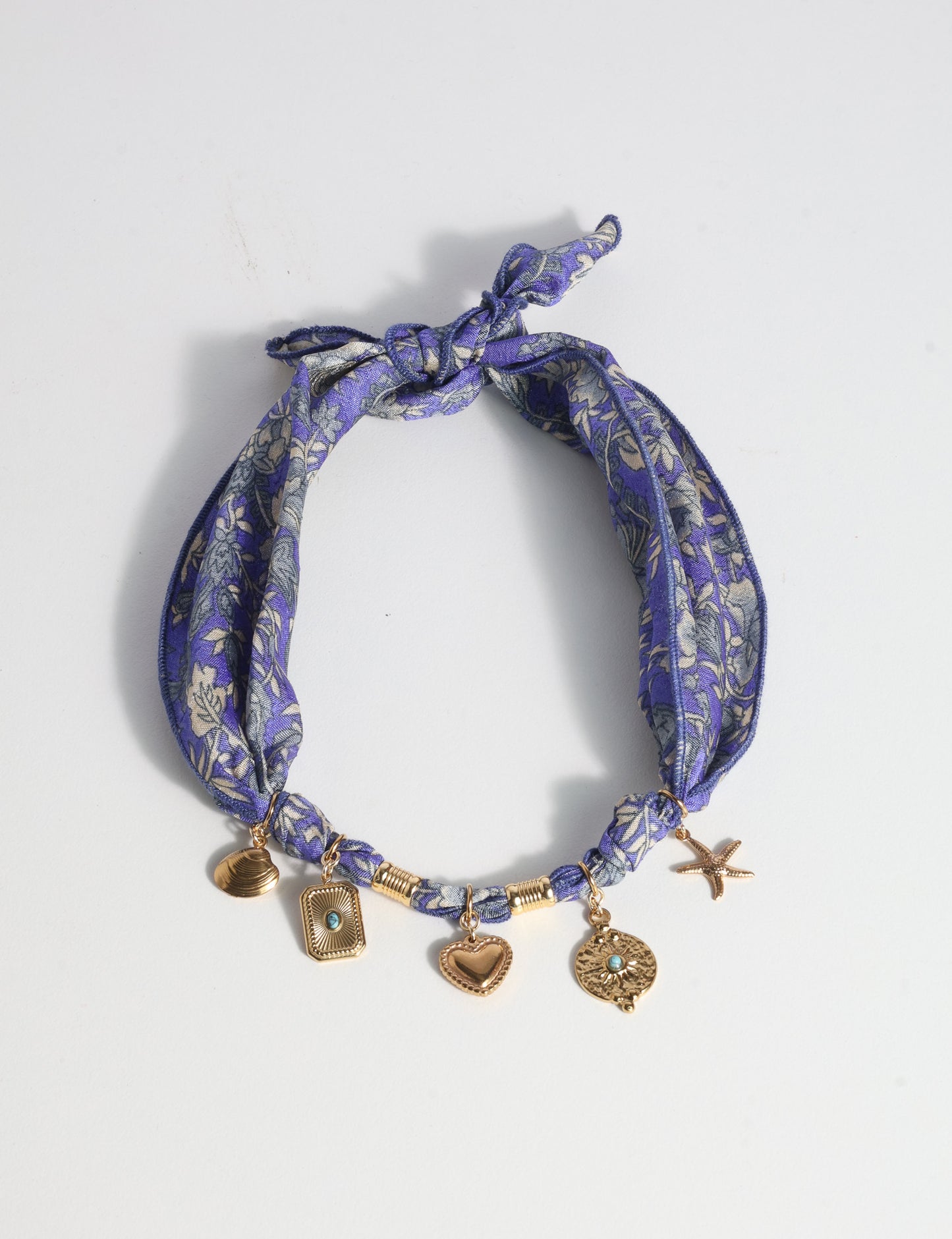 Bandana necklace with gold-plated charms, adjustable tie-back design, stainless steel hardware, handmade statement necklace, sustainable fashion accessory.