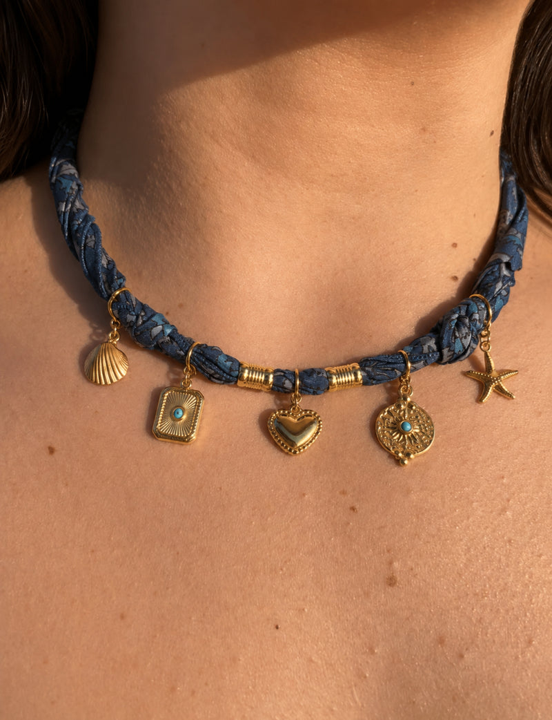 Grey tropical patterned bandana necklace worn on neck with gold shell, heart, starfish, and decorative charms hanging