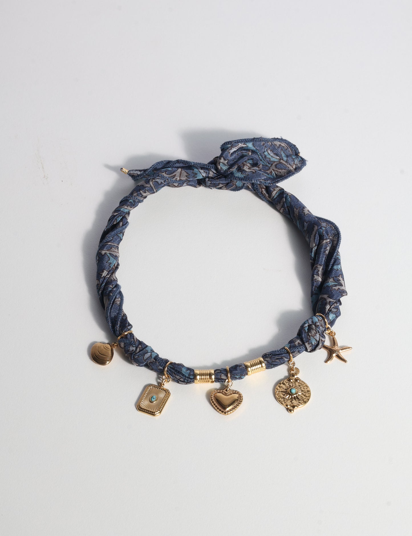 Bandana necklace with gold-plated charms, adjustable tie-back design, stainless steel hardware, handmade statement necklace, sustainable fashion accessory.