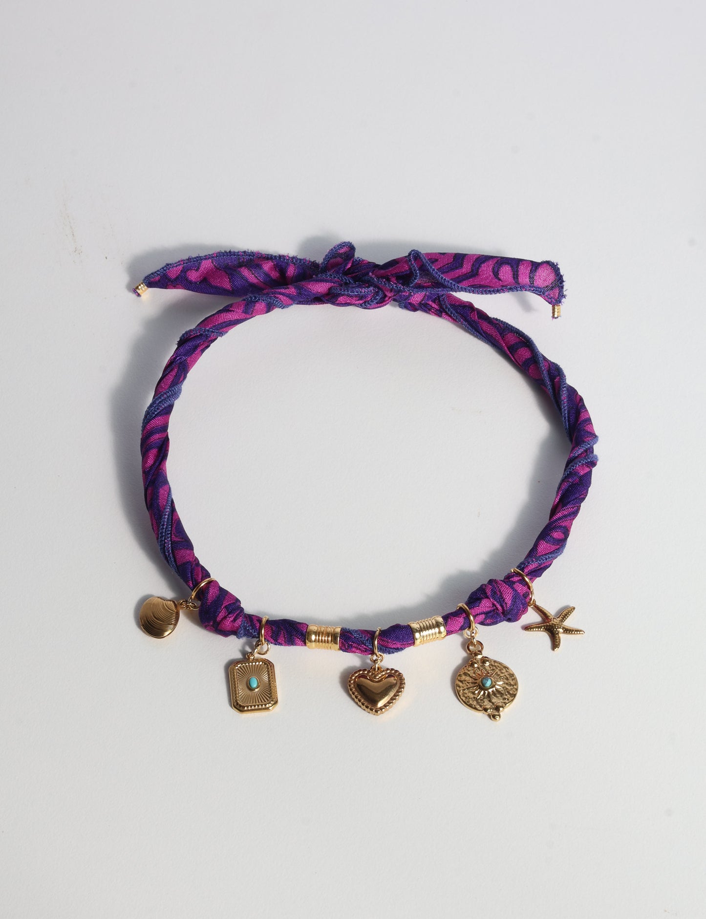 Bandana necklace with gold-plated charms, adjustable tie-back design, stainless steel hardware, handmade statement necklace, sustainable fashion accessory.