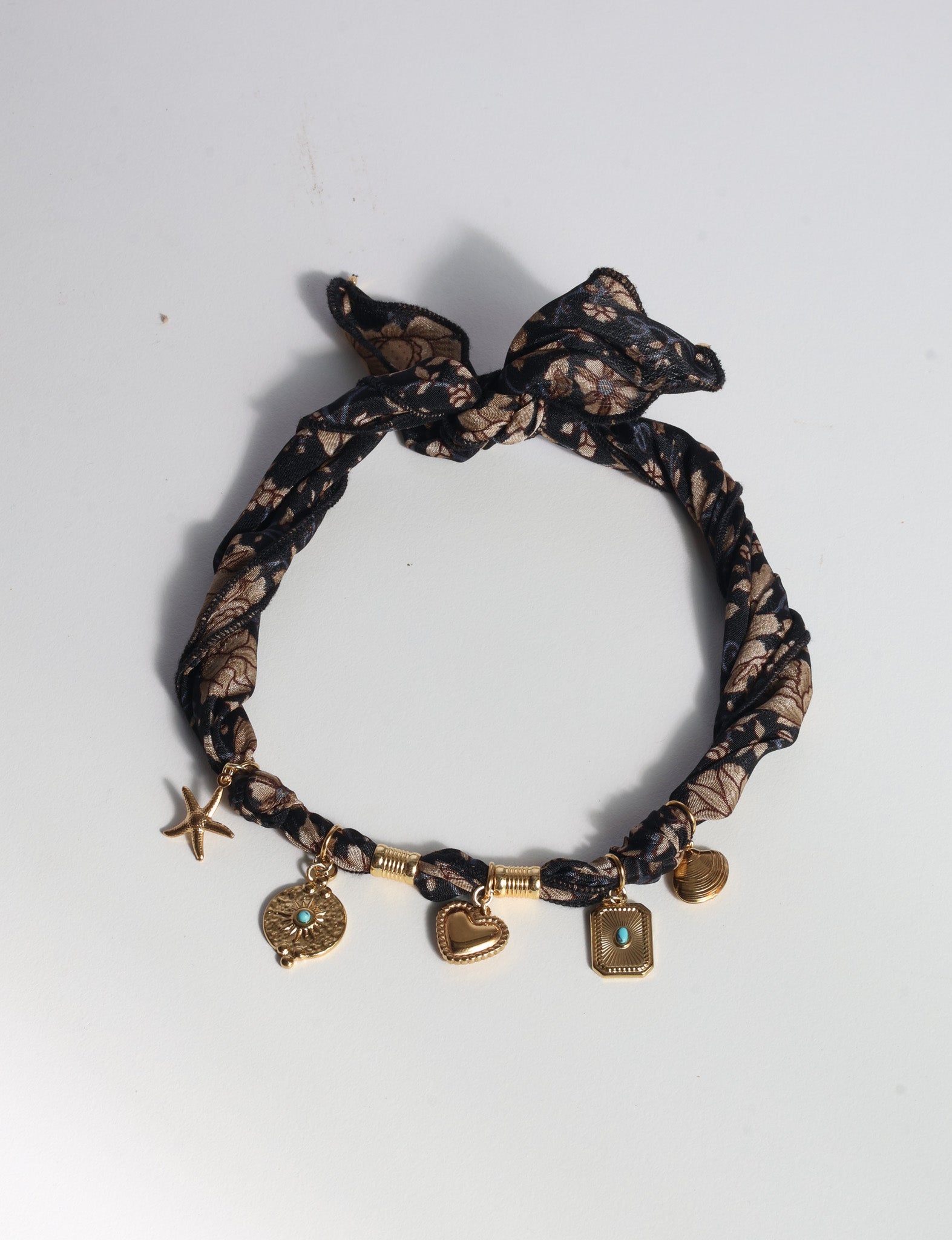 Black tropical patterned bandana necklace with gold-tone charms including starfish, heart, and rectangular pendants