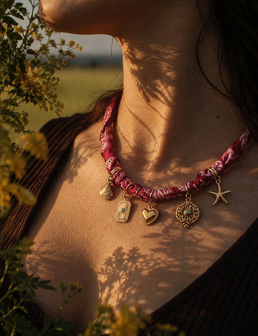 Bandana necklace with gold-plated charms, adjustable tie-back design, stainless steel hardware, handmade statement necklace, sustainable fashion accessory.