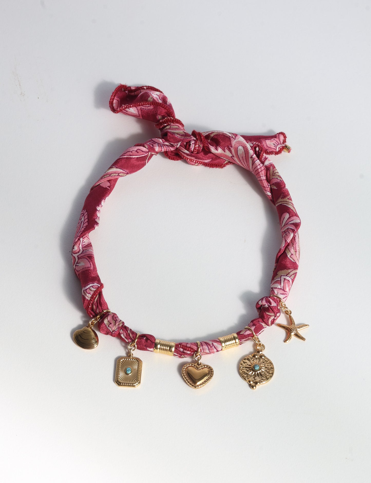 Bandana necklace with gold-plated charms, adjustable tie-back design, stainless steel hardware, handmade statement necklace, sustainable fashion accessory.