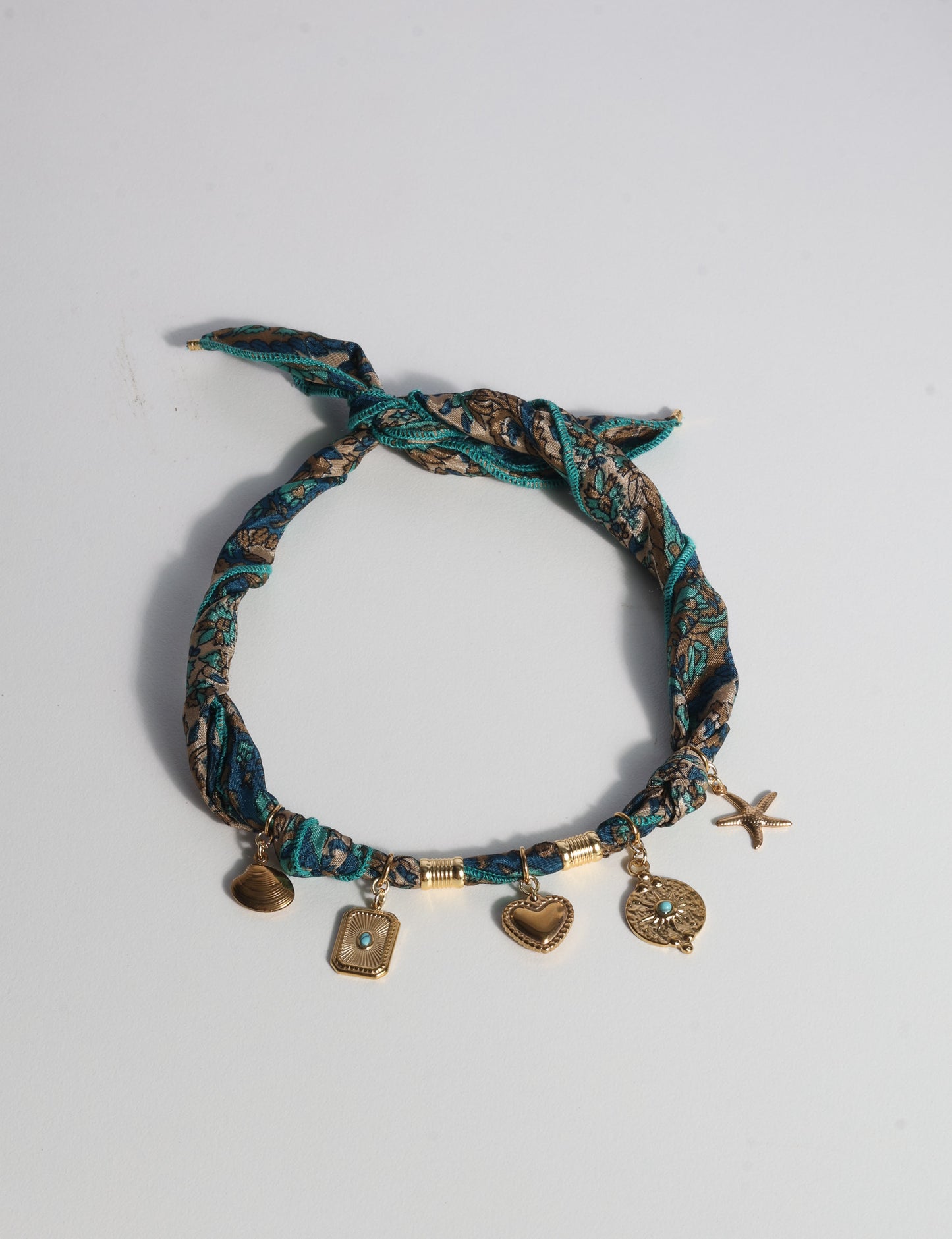 Bandana necklace with gold-plated charms, adjustable tie-back design, stainless steel hardware, handmade statement necklace, sustainable fashion accessory.