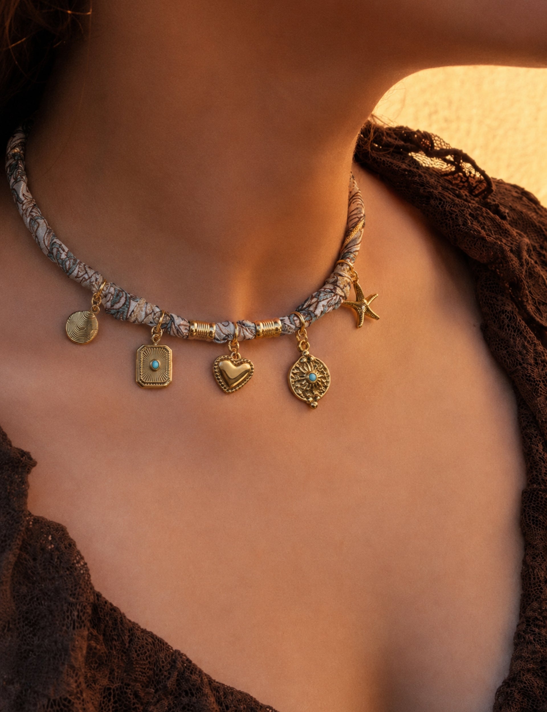 Beige tropical patterned bandana necklace with gold-tone charms including heart, starfish, and turquoise accents worn by model