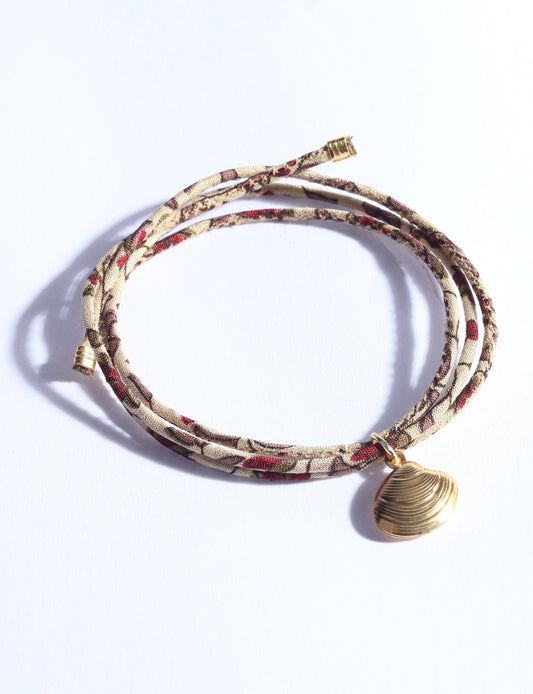 Adjustable slim cord bracelet with gold-plated stainless steel shell charm inspired by upcycled women’s clothing, sustainable women’s clothing, eco friendly clothes, recycled sustainable fashion, carbon neutral clothing, and environment friendly clothing values.