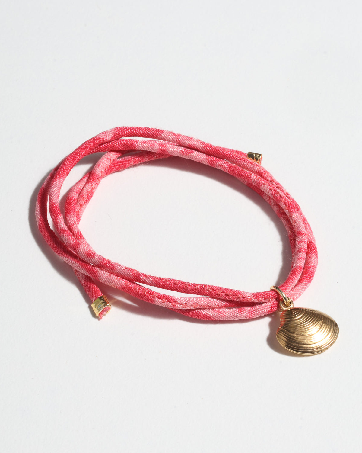 Red tropical cord bracelet with gold-tone shell charm and gold-tone end caps, shown flat on white background