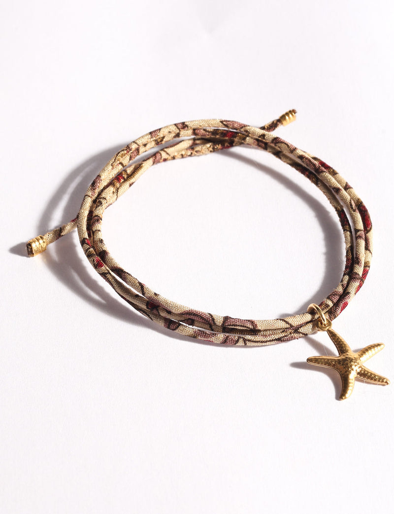 Beige and brown patterned cord bracelet with gold-tone starfish charm, shown flat on white background