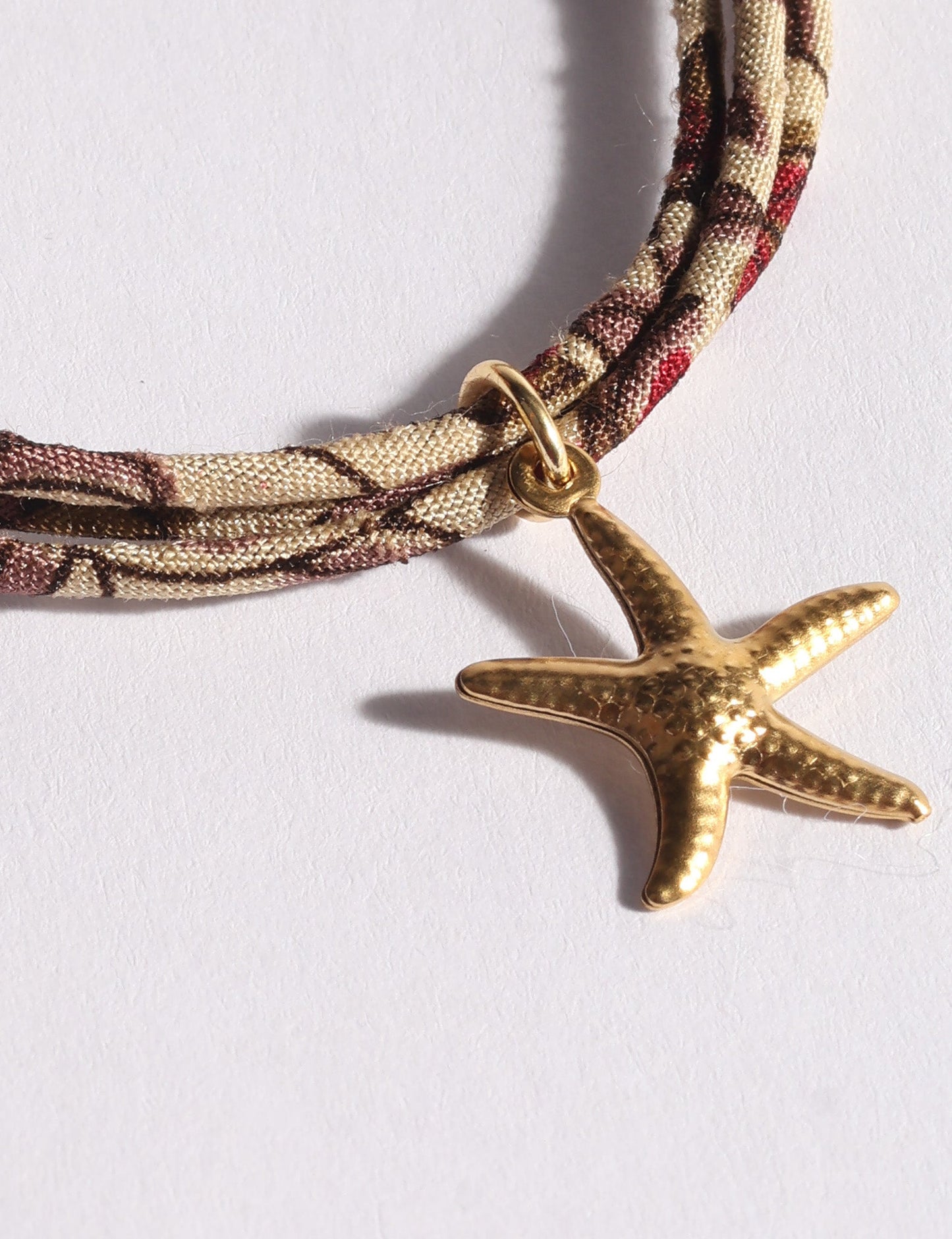 Slim adjustable cord bracelet with gold-plated stainless steel star fish charm inspired by upcycled women’s clothing, sustainable women’s clothing, eco friendly clothes, recycled sustainable fashion, carbon neutral clothing, and environment friendly clothing values.