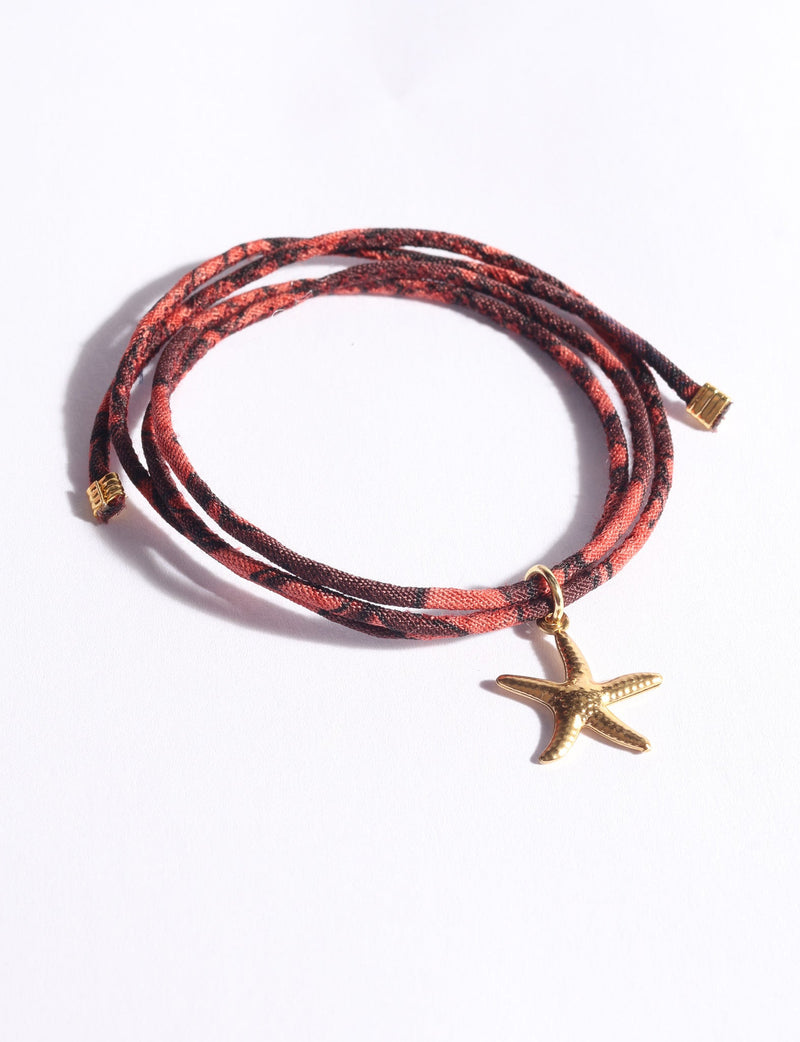 Red and black patterned cord bracelet with gold starfish charm and gold end caps, shown flat on white background