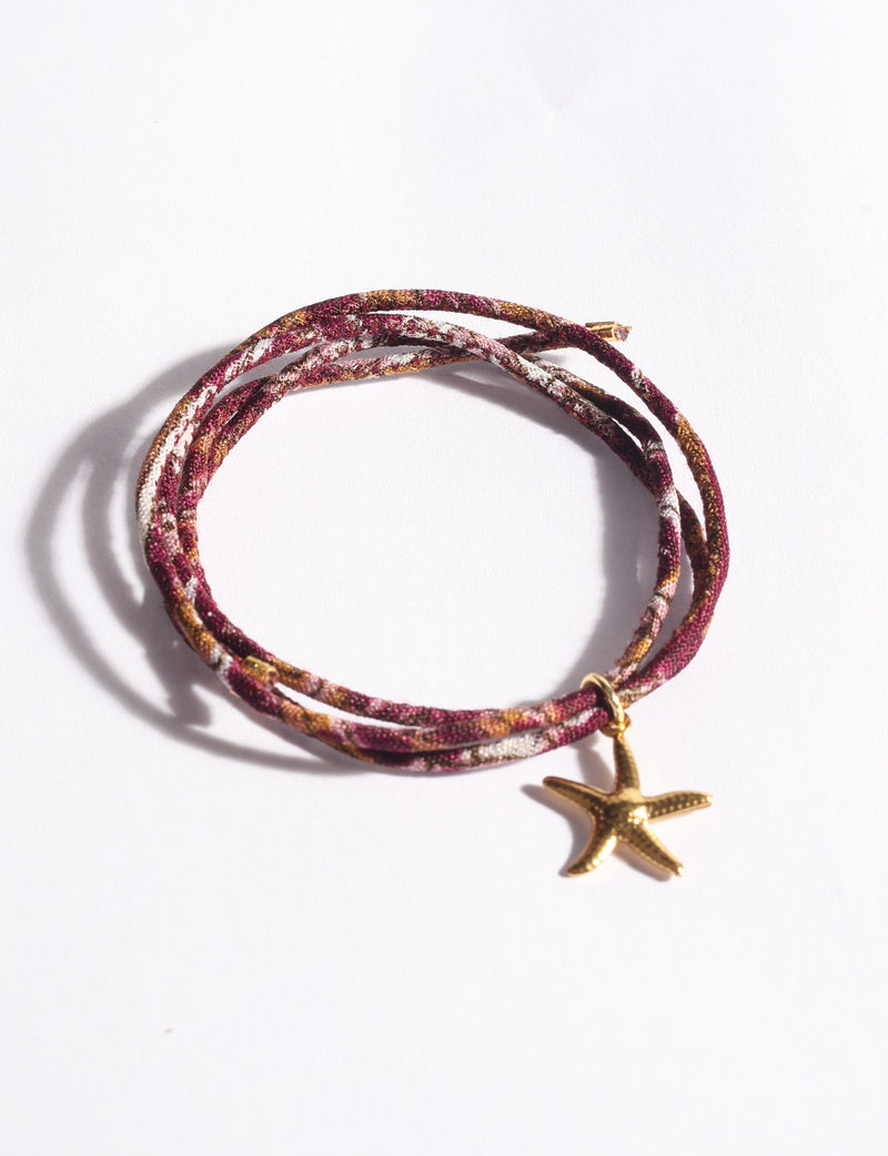 Multicolor cord bracelet with gold-tone starfish charm, shown coiled on white background, close-up front view