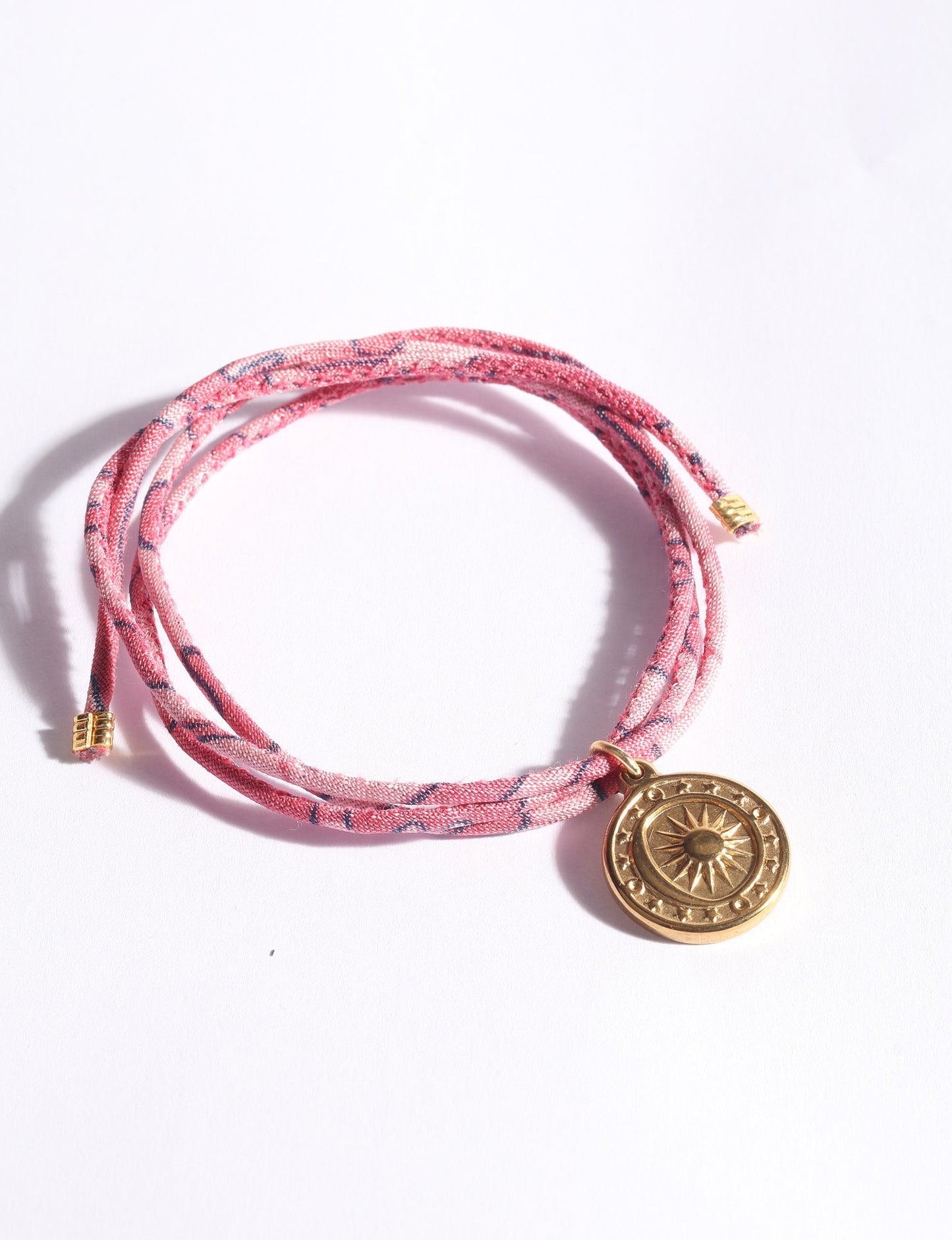 Slim adjustable cord bracelet with gold-plated stainless steel sun charm, inspired by upcycled women’s clothing, sustainable women’s clothing, eco friendly fashion, recycled sustainable fashion, carbon neutral fashion, and environment friendly clothing values.