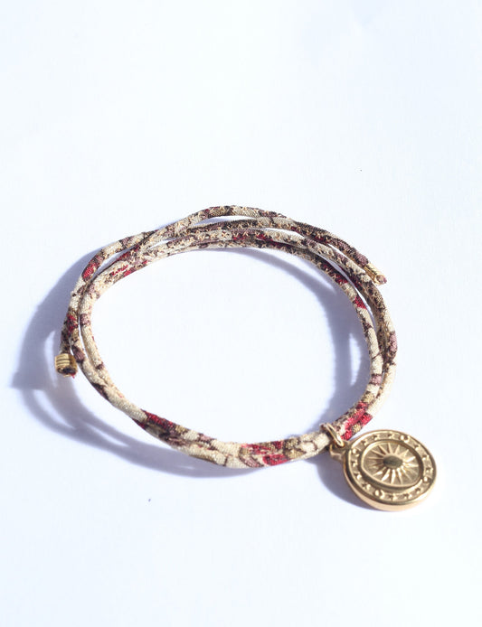 Slim adjustable cord bracelet with gold-plated stainless steel sun charm, inspired by upcycled women’s clothing, sustainable women’s clothing, eco friendly fashion, recycled sustainable fashion, carbon neutral fashion, and environment friendly clothing values.