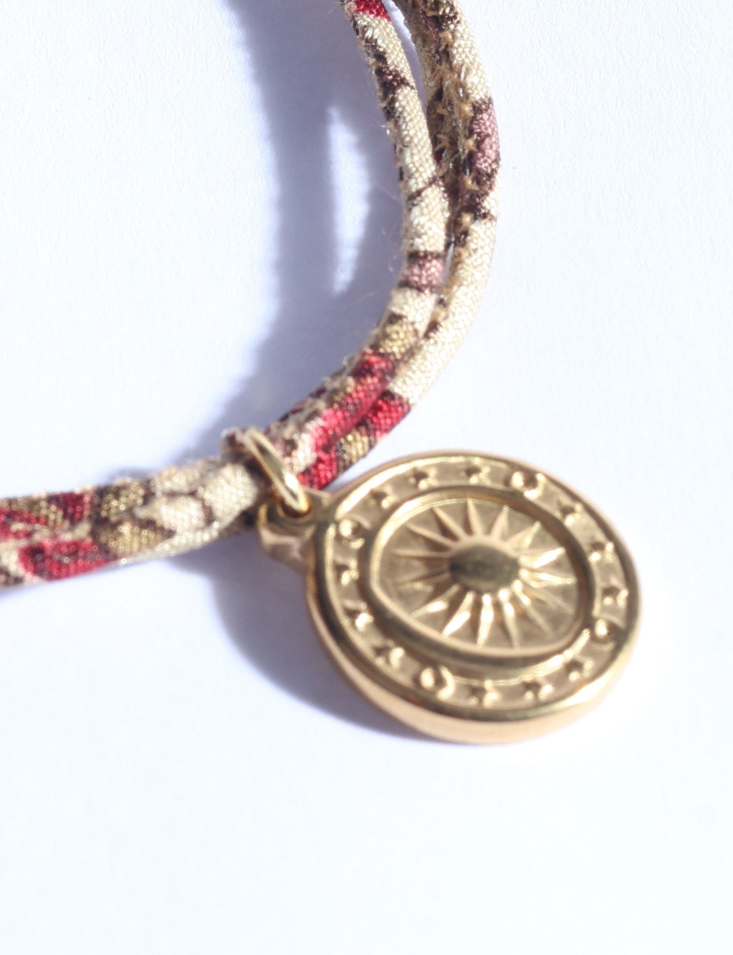 Slim adjustable cord bracelet with gold-plated stainless steel sun charm, inspired by upcycled women’s clothing, sustainable women’s clothing, eco friendly fashion, recycled sustainable fashion, carbon neutral fashion, and environment friendly clothing values.