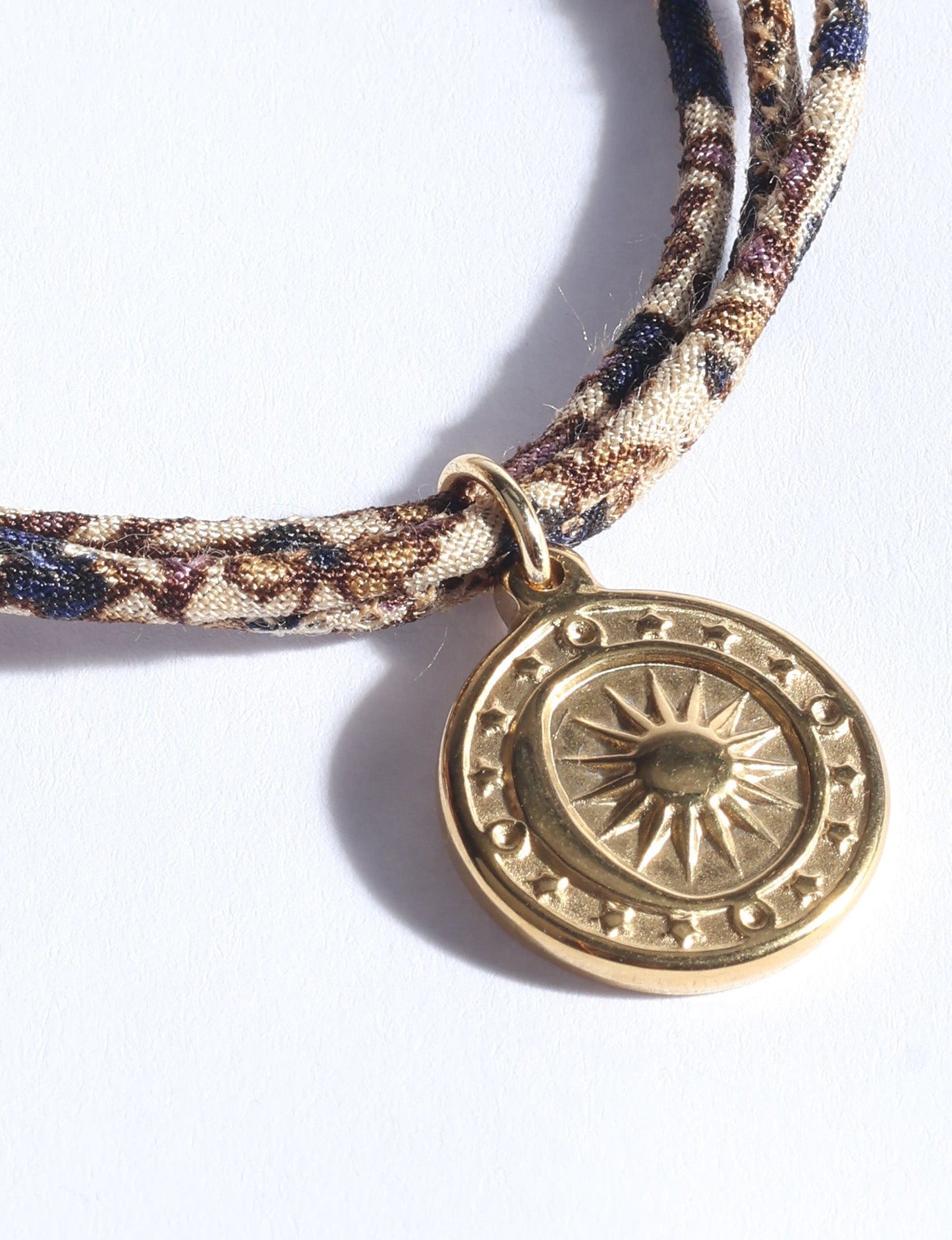 Slim adjustable cord bracelet with gold-plated stainless steel sun charm, inspired by upcycled women’s clothing, sustainable women’s clothing, eco friendly fashion, recycled sustainable fashion, carbon neutral fashion, and environment friendly clothing values.