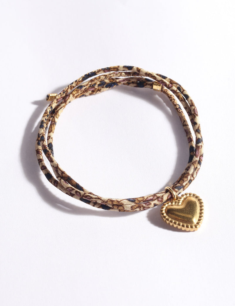 Beige abstract patterned cord bracelet with gold-tone heart charm, shown flat on white background