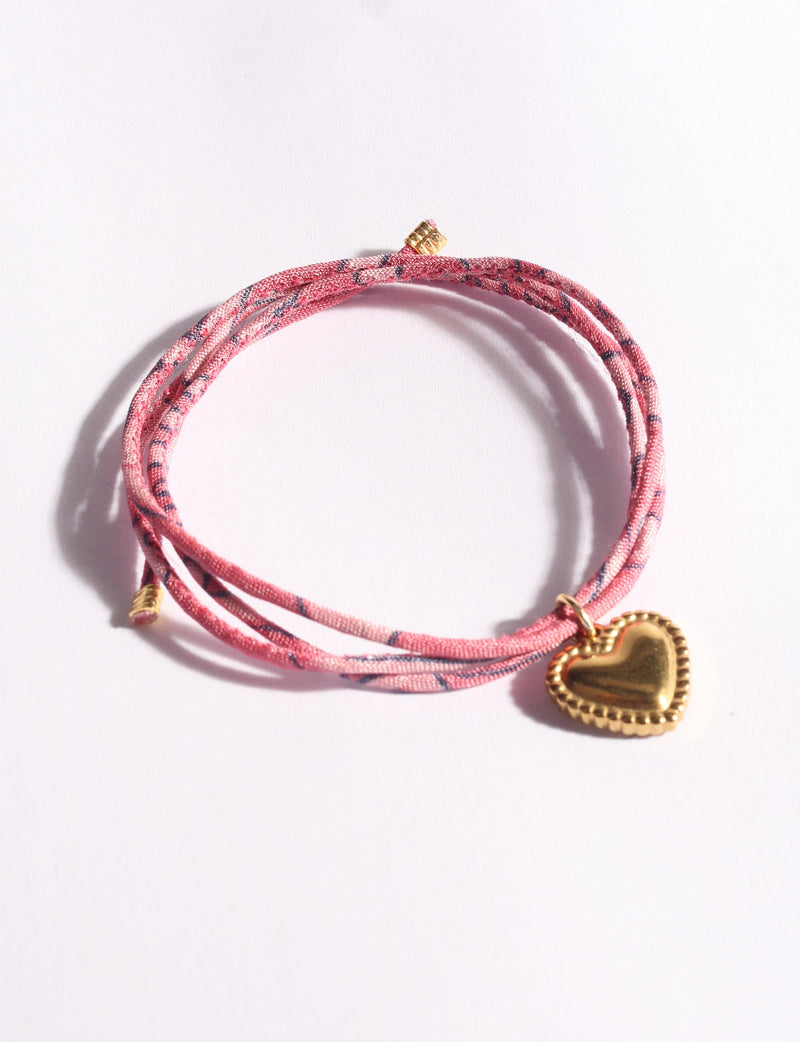 Pink abstract patterned cord bracelet with a gold-tone heart charm, shown flat on a white background