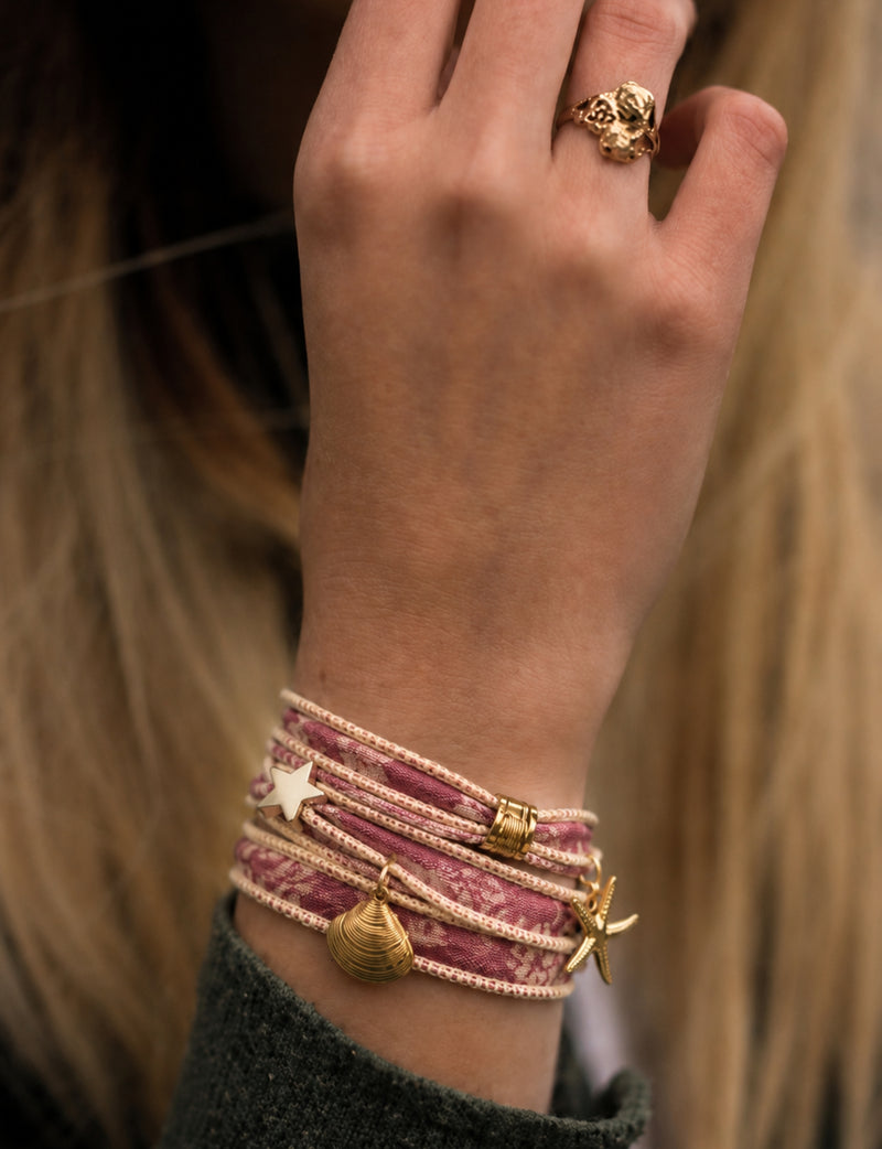 Wrap-around bracelet with orange abstract fabric and gold-tone star, shell, and starfish charms worn on wrist