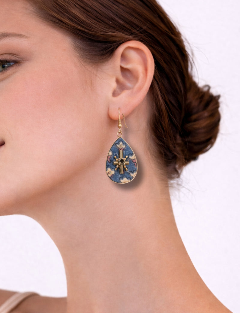 Woman wearing teardrop-shaped earrings with grey fabric and floral micro design, gold-tone metal accents, side view
