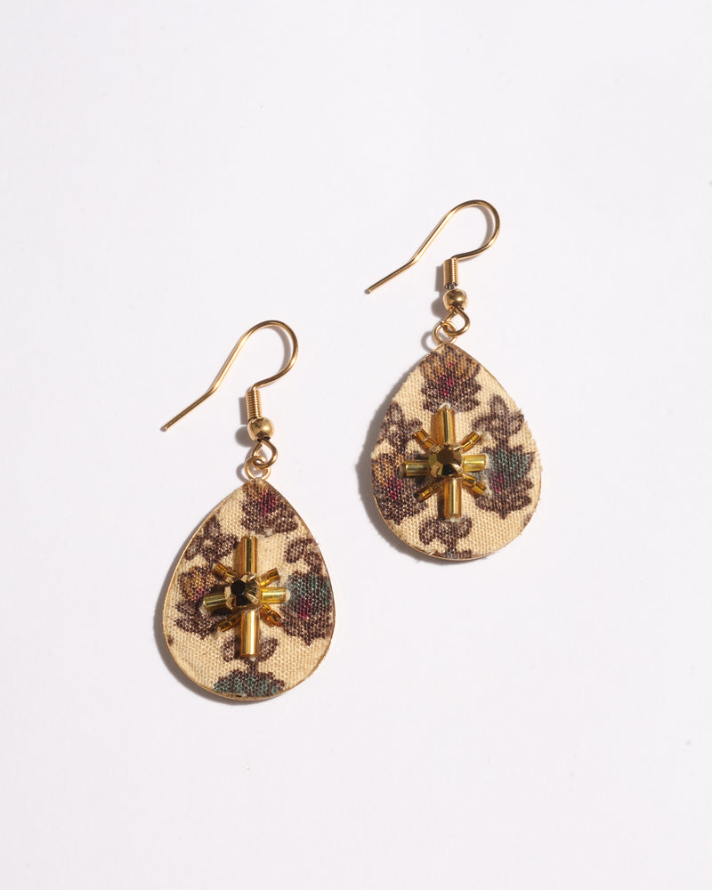 Beige teardrop earrings with tropical floral fabric pattern and gold bead embellishment, shown flat on white background