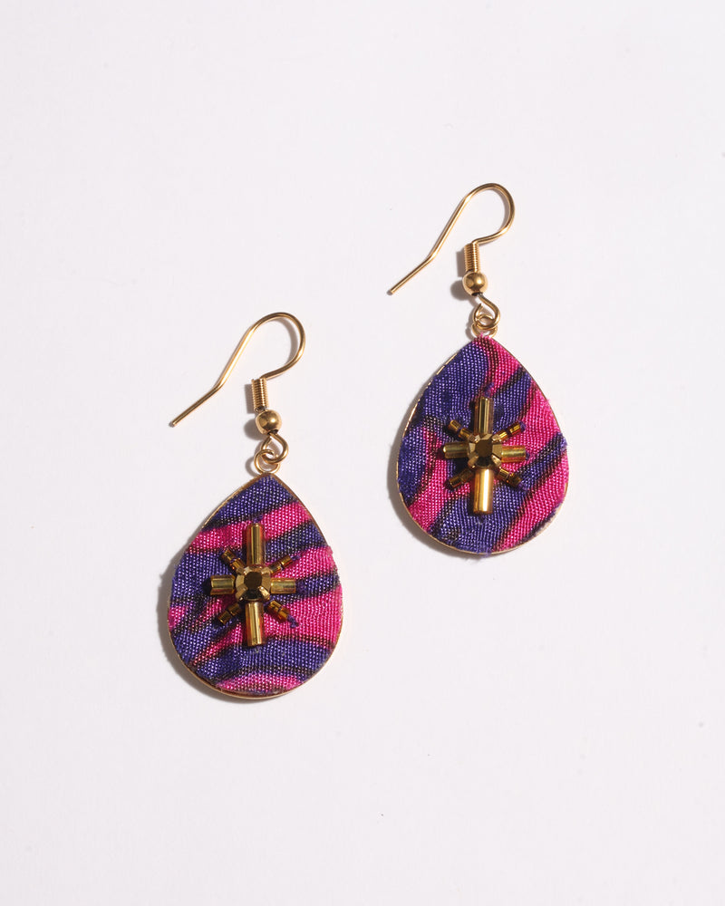 Teardrop-shaped earrings with pink and purple abstract fabric and gold bead cross embellishments, shown flat on white background