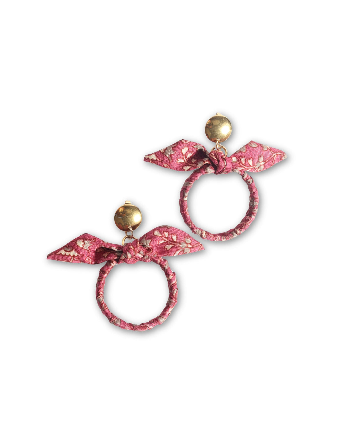 Pink tropical fabric bow earrings with gold-tone round studs and fabric-wrapped circular hoops, flat lay on white background