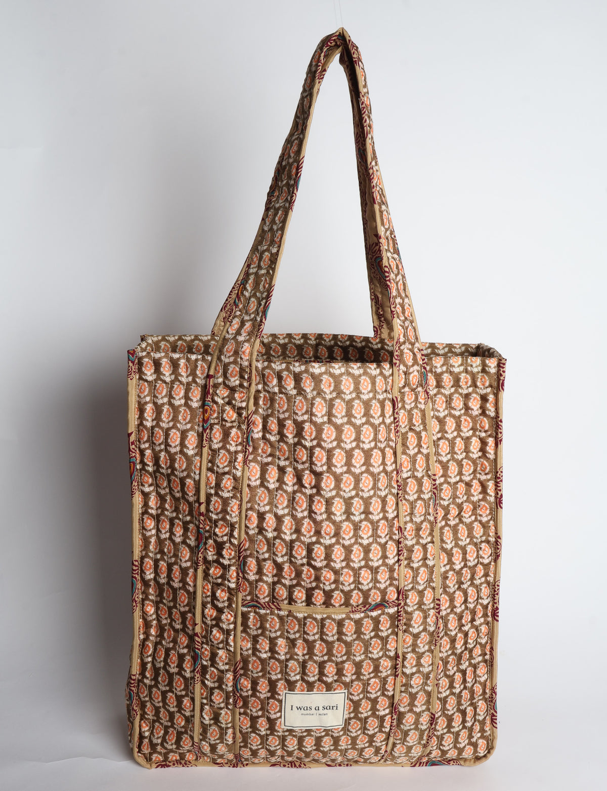 Quilted carry-all tote bag with a structured rectangular shape, long shoulder straps, and an external patch pocket.